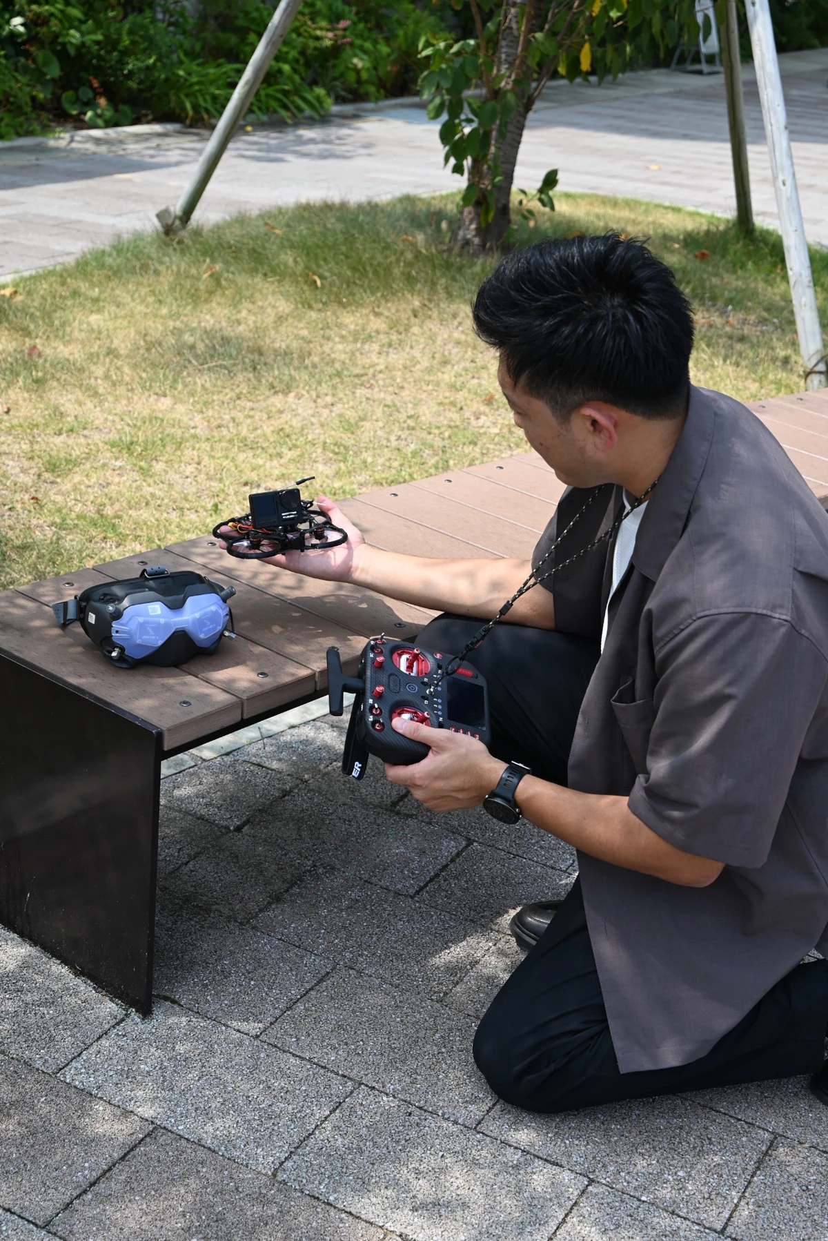 屋外でしゃがみ、手のひらにFPVドローンを載せて送信機を操作するU-NINES代表・川原亮太